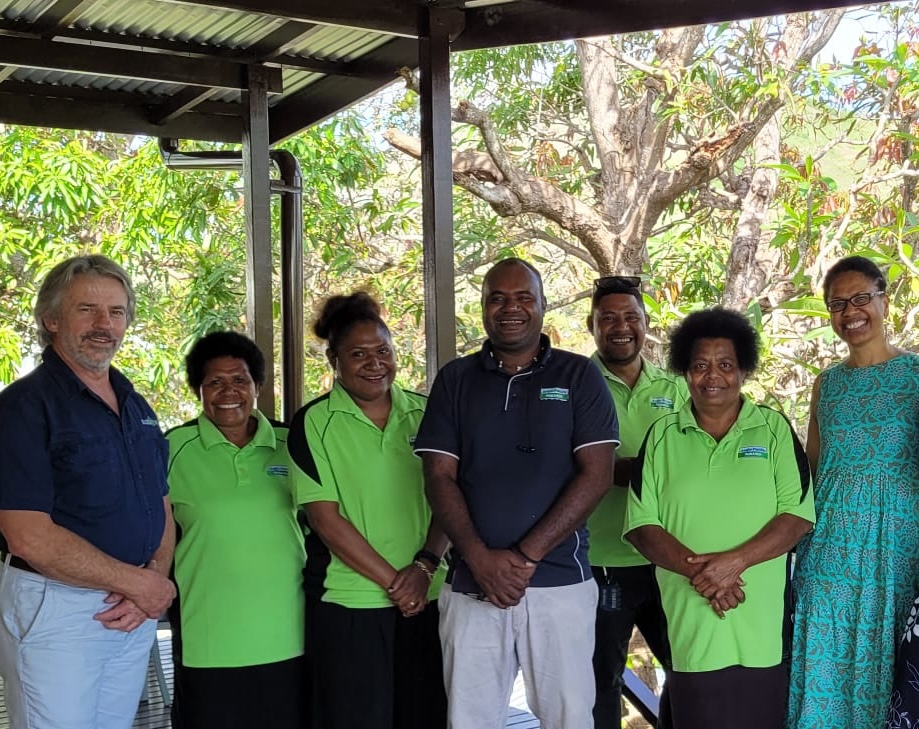 Photo of the APR team under a pergola with trees in the background